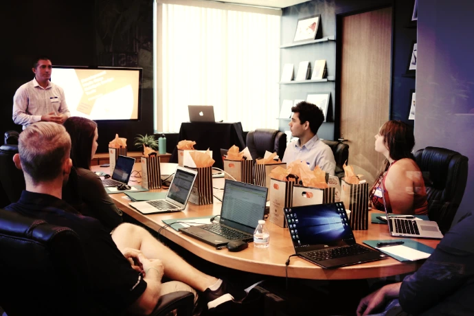 man standing in front of people sitting beside table with laptop computers